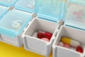 Plastic box with different pills on yellow background, closeup Royalty Free Stock Photo