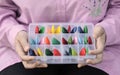 Plastic box with the embroidery threads is in female hands, close-up