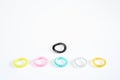 Plastic bracelets of various colors, isolated in a pattern arranged in white background, with a black to be different Royalty Free Stock Photo