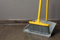 Plastic broom with dustpan near grey wall indoors. space for text