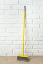 Plastic broom near white brick wall indoors Royalty Free Stock Photo