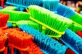 Plastic brushes for cleaning premises. Assortment of multi-colored brooms in the store. Close-up Royalty Free Stock Photo