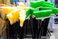 Plastic brushes for cleaning premises. Assortment of multi-colored brooms in the store. Close-up Royalty Free Stock Photo
