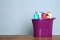 Plastic bucket with different cleaning products on table against color background Royalty Free Stock Photo