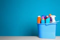 Plastic bucket with different cleaning products on table against color background Royalty Free Stock Photo