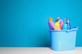 Plastic bucket with different cleaning products on table against color background Royalty Free Stock Photo