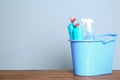 Plastic bucket with different cleaning products on table against color background. Space for Royalty Free Stock Photo