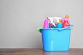 Plastic bucket with different cleaning products on table against light background Royalty Free Stock Photo