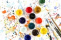 Jars with gouache paints and brushes on colorful paint splashes background. Royalty Free Stock Photo