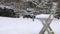 Plastic chair covered with snow in garden and snoflakes snow fall on background