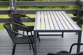 Plastic chairs and wooden table on WPC flooring terrace outdoors.