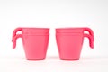 Plastic children`s mugs of pink color on a white background Royalty Free Stock Photo