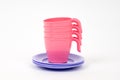 Plastic children`s pink mugs and lilac plates on a white background Royalty Free Stock Photo