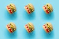 Plastic childrens toy burger with salad, tomato, meat with on pastel blue background. Concept of harmful artificial food.