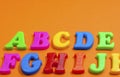 Plastic color letters on a bright contrasting orange background, multicolored alphabet Royalty Free Stock Photo