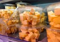 Plastic container with cubes of cheese in it is being sold without visible marks or brands on a supermarket shelf