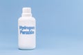 Plastic container, medicine bottle, written in english: hydrogen peroxide, isolated blue background, concept of first care