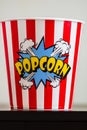 Plastic container for popcorn isolated close up photo. Popcorn sign on plastic and empty red and white striped bucket. Movie time