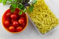 plastic container with two types of pasta ,bowl with ripe tomatoes and fresh basil leaves Royalty Free Stock Photo