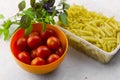 Plastic container with two types of pasta ,bowl with ripe tomatoes and fresh basil leaves Royalty Free Stock Photo