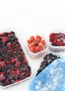 Plastic containers of frozen mixed berries in snow