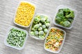 Plastic containers with frozen vegetables on grey background, top view, Different frozen vegetables on table, corn brussels Royalty Free Stock Photo