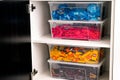 Plastic containers full of blue, red, yellow and brown Lego blocks, bricks and toys stacked in a cupboard