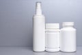 3 plastic containers for medicines and vitamins, a bottle with a spray bottle on a gray background Royalty Free Stock Photo