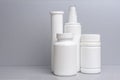 4 plastic containers for medicines and vitamins, a bottle with a spray bottle on a gray background. white cans without a name Royalty Free Stock Photo