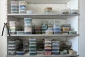 Plastic containers with smalt on shelves in closet. Regular or irregular pieces of colored stone or ceramic known as smalt for Royalty Free Stock Photo