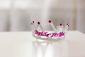 Plastic crowned jewel crown or tiara with purple beads on a white background with the word bride to be