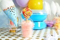 Plastic cup with cotton candy and candies on table