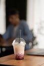 Plastic cup of fresh bubble drinks on wooden table in cafe over male client background