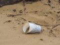 Plastic cup left on the beach discarded by uncaring people Royalty Free Stock Photo