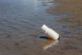 Plastic cup left on the beach after the tourists have taken a vacation. Garbage on the sandy beach. Plastic glass in the sea Royalty Free Stock Photo