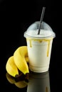 Plastic cup of milkshake with banana isolated on balck background Royalty Free Stock Photo