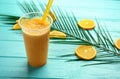 Plastic cup of tasty orange smoothie on color wooden table Royalty Free Stock Photo