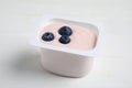 Plastic cup with tasty yogurt and blueberries on white wooden table