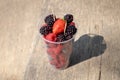 Plastic cup with toothpicks and mixed berries -  blackberries, raspberries, strawberry on wooden table Royalty Free Stock Photo