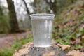 Plastic cup with water on a wooden log Royalty Free Stock Photo