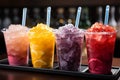 Plastic cups hold frozen fruit slushies, aligned in a colorful, frosty row Royalty Free Stock Photo