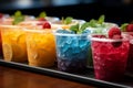 Plastic cups hold frozen fruit slushies, aligned in a colorful, frosty row Royalty Free Stock Photo