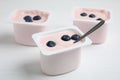 Plastic cups with tasty yogurts and blueberries on white wooden table