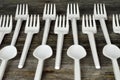 Plastic cutlery. Disposable plastic forks and spoons on wooden background