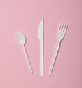 Plastic cutlery for picnics on a pink background. Disposable spoon, fork, knife. Top view, copy space Royalty Free Stock Photo