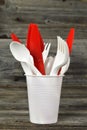 Plastic cutlery on wooden background. Forks, spoons and knives in disposable plastic cup Royalty Free Stock Photo