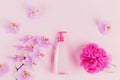 Plastic dispenser bottle with cosmetic soap, shampoo or shower gel, pink sponge and purple orchid flowers on pink background. Spa Royalty Free Stock Photo