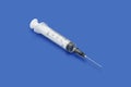 Plastic disposable syringe with a needle on blue background