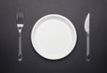 Plastic disposable tableware. Plate, fork and knife on black background Royalty Free Stock Photo