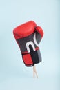 Plastic doll legs in heavy staggering boxing glove on minimal blue background